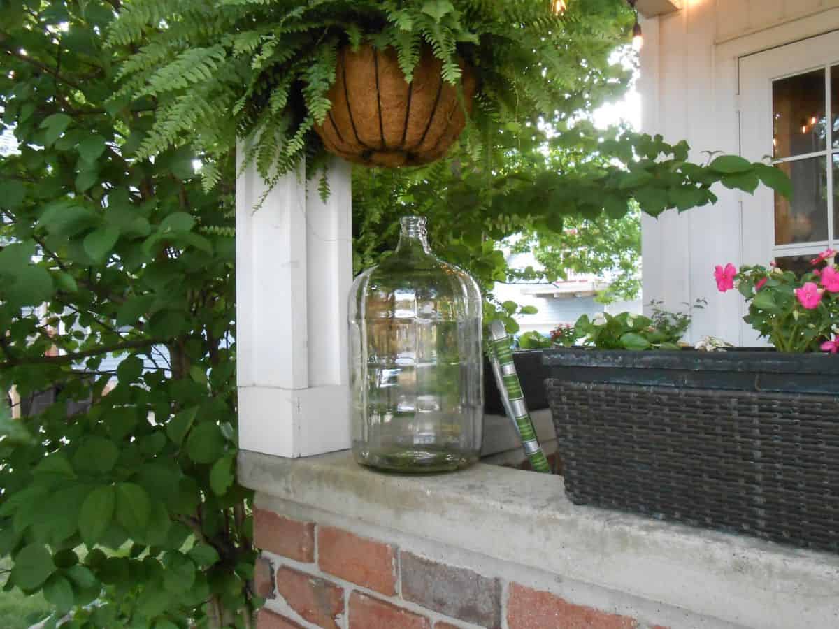 Vintage glass carboy container on a porch.