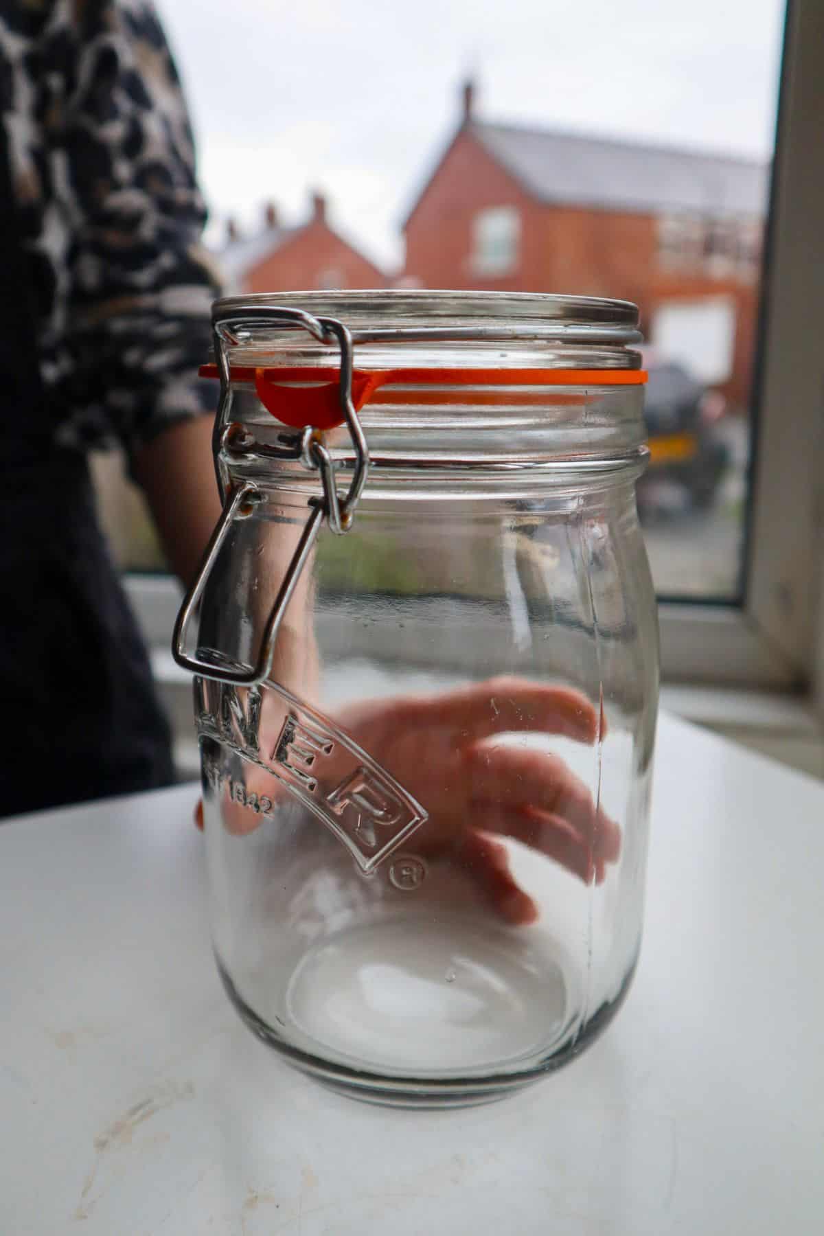 Empty glass mason jar with hand