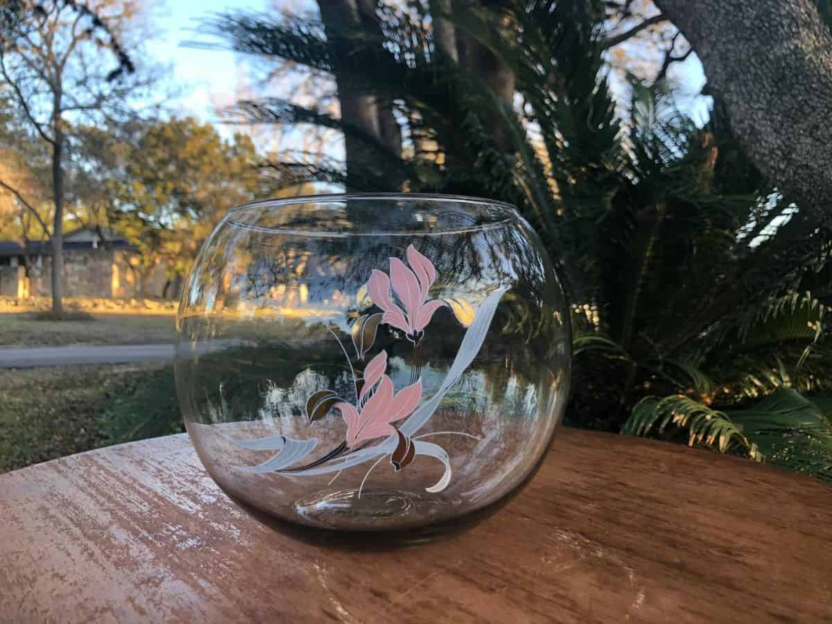 Clear glass fishbowl with floral design on the side in pink, grey, and brown