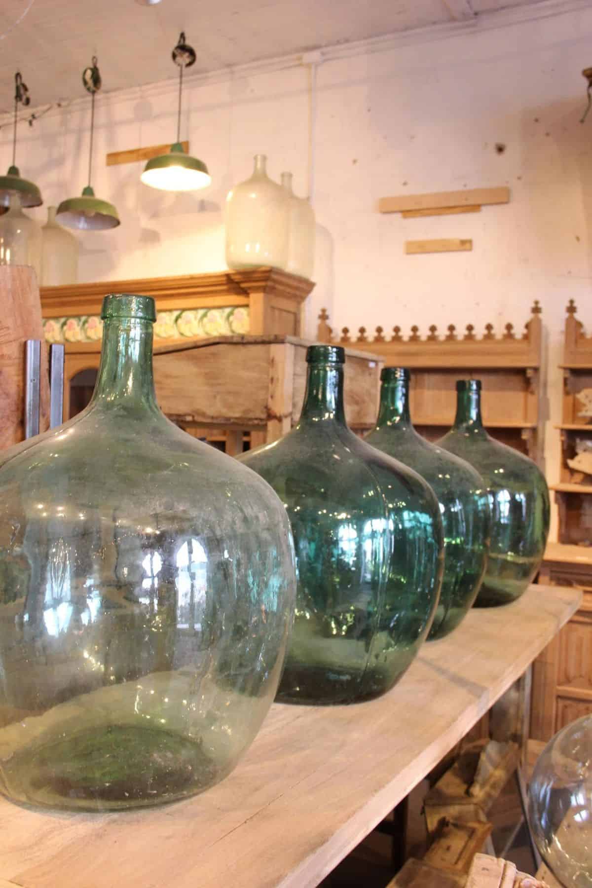 Workshop shelf with four large green demijohn bottles on