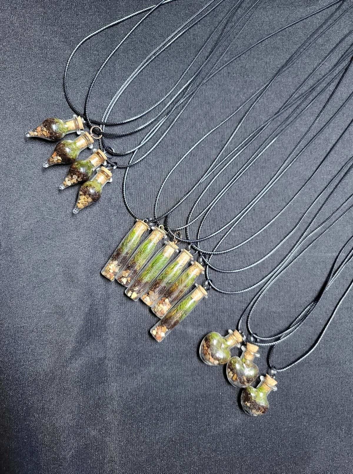 Several terrarium necklaces laid out on table 