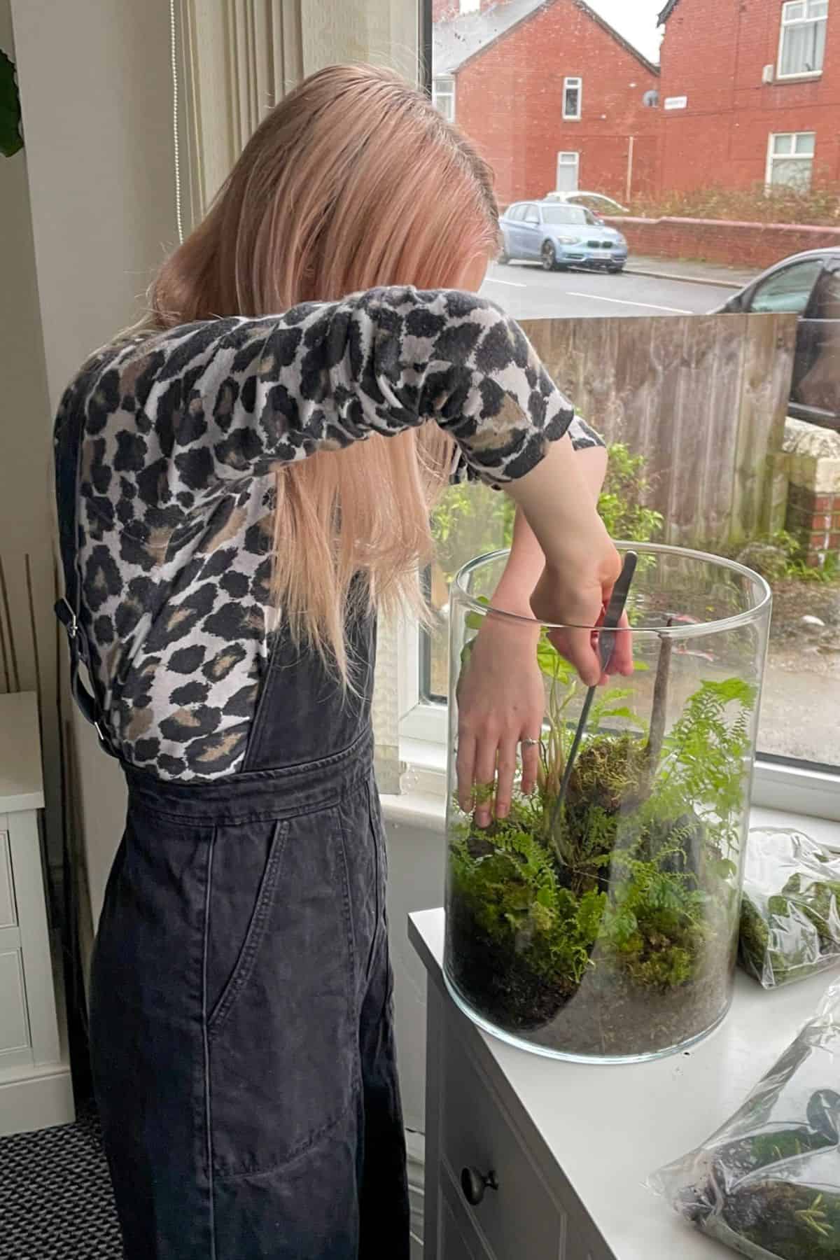 Person reaching elbows up to maintain terrarium