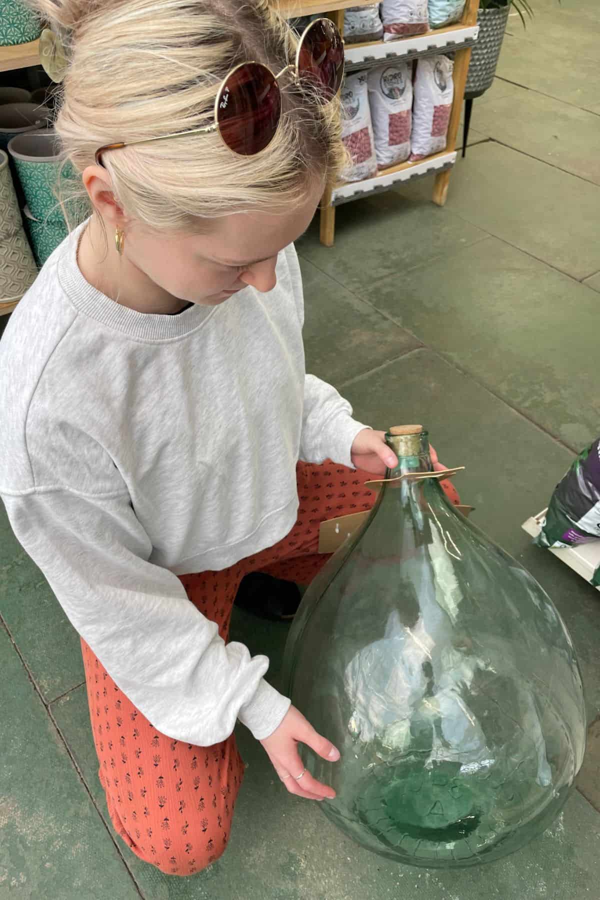 Person in garden center holding demijohn container